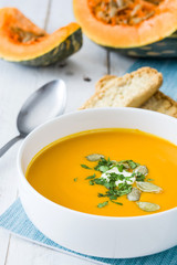 Pumpkin soup and ingredients on white wooden background

