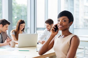 Businesswoman talking on cell phone while working with business team