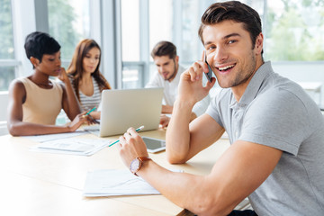 Obraz premium Businessman talking on mobile phone while working with business team