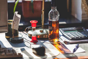Bottle of alcohol and hourglass on your desktop