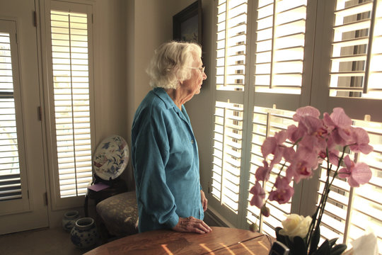 Older Caucasian woman looking out window