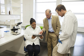Businessman and scientists using digital tablet in laboratory