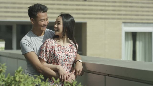 Happy romantic couple in new apartment looking at the view from roof terrace