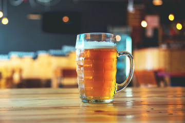 Beautiful background of the Oktoberfest. Glass of cold fresh lager beer on a wooden bar counter in pub with free space for your text