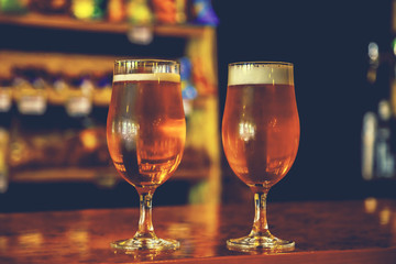 Two glasses of fresh cold light beer on a wooden bar counter in pub with free space for your text. Beautiful background of the Oktoberfest.