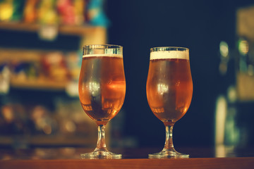Two glasses of fresh cold light beer on a wooden bar counter in pub with free space for your text. Beautiful background of the Oktoberfest.