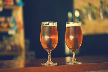 Two glasses of fresh cold light beer on a wooden bar counter in pub with free space for your text. Beautiful background of the Oktoberfest.