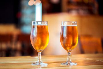 Two glasses of fresh cold light beer on a wooden bar counter in pub with free space for your text. Beautiful background of the Oktoberfest.