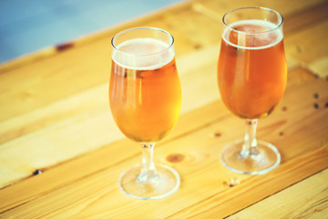 Beautiful background of the Oktoberfest. Two glasses of cold fresh light beer on the wooden bar counter in the pub. Assorted alcohol in a Flight Ready for Tasting