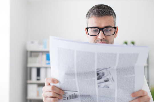 Confident businessman reading a newspaper