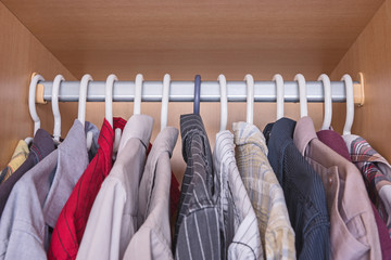 Selection of men's shirts hanging inside a wardrobe