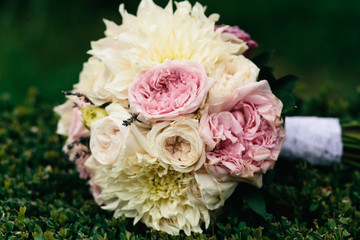 Bouquet made of pink and white pionies lies on a green lawn