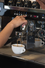 The worker prepares coffee with cream on the coffee machine