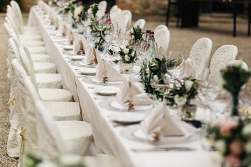 Chairs covered with white cloth stand at a table ready for a wed