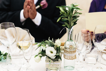 Glass bottles used as flower vases stand on the dinner table
