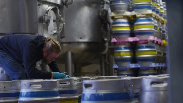  Worker in a brewery preparing barrels of beer for distribution