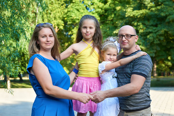 Fototapeta premium happy family posing on outdoor, group of four people portrait in city park, summer season, child and parent