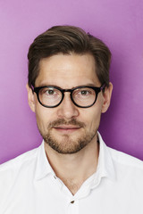 Obraz premium Handsome man in spectacles, portrait against purple