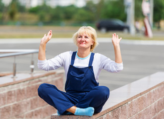 Portrait of the happy woman in the uniform sitting in a lotus pose.