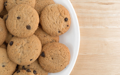 Vanilla chocolate chip crunchy cookies on a plate atop a wood table.