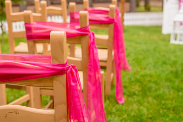 Fototapeta na wymiar wooden decorated empty chairs on a lawn before wedding ceremony