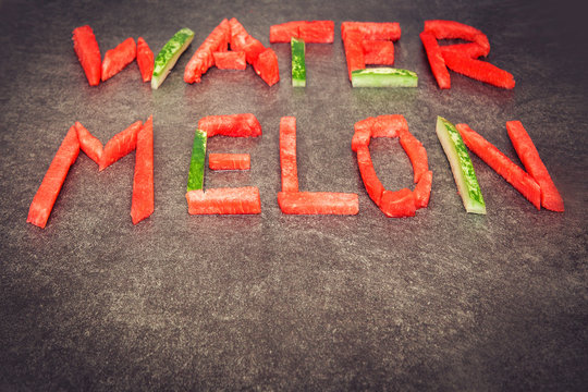 Lettering watermelon. Word watermelon composed of it pieces. For alphabet. Gray stone background. Horizontal. Copy space below,