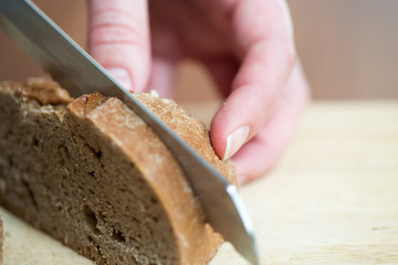 Hands cutting rye bread on a table