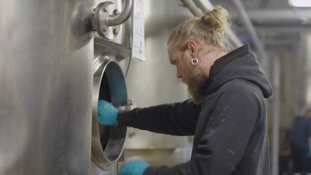  Worker in a brewery checking the machines & looking at clipboard