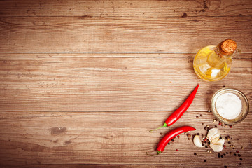 Seasoning, olive oil, chili peppers, garlic on dark wooden background. Copy space left.