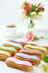 Eclairs with glaze on a white wooden table