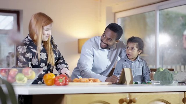  Happy mixed ethnicity family preparing a meal together in kitchen