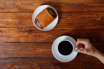 Woman's hand with cup of coffee and croissant, top view