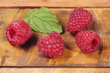 Gruppe Himbeeren mit Minzblatt auf Holzbrett