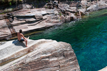 Lavertezzo, Svizzera: un ragazzo su una roccia nel canyon del fiume Verzasca il 29 luglio 2016. Il Verzasca è un fiume il cui nome deriva dal colore verde dell’acqua