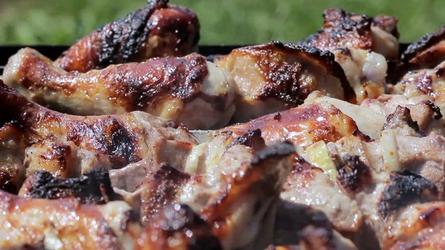Chicken and pork grilled on charcoal in a barbecue. Meat rotates and has golden skin. moving the camera. Close up
