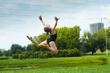 Young beautiful preteen girl doing gymnastics outdoors