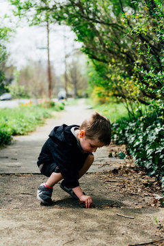 Boy picking up sticks on pavement