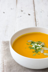 Pumpkin soup and ingredients on a white wooden table

