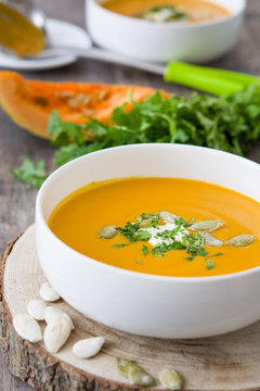 Pumpkin soup and ingredients on a rustic wooden table

