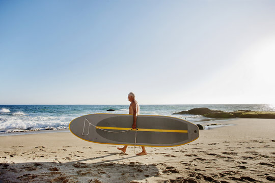 Caucasian man carrying paddleboard