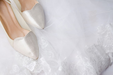 Close-up of wedding shoes on lace wedding veil with white wooden