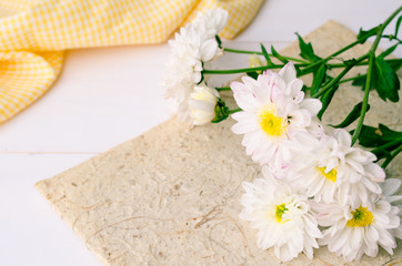 White chrysanthemum flowers with yellow fabric on wooden backgro