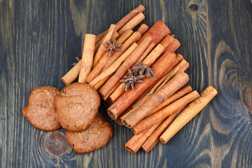 Cinnamon sticks with star anise and cookies on wooden table