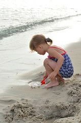 Beautiful little girl playing on the beach.