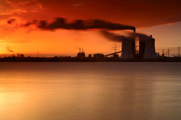 Coal Power Plant on a Lake at Sunrise, Exhaust Fumes blown by Storm, long exposure
