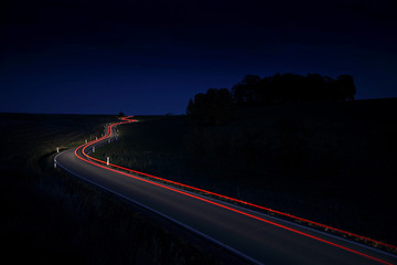 Car Driving Down a Winding Country Road, long exposure, Taillights in blurred motion