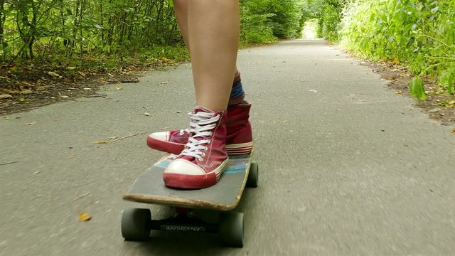 
4K. Young beautiful  slender girl  goes on  skateboard in summer park
