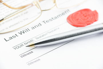 Blue ballpoint pen on last will and testament with eye glasses and a sealing wax stamped with...
