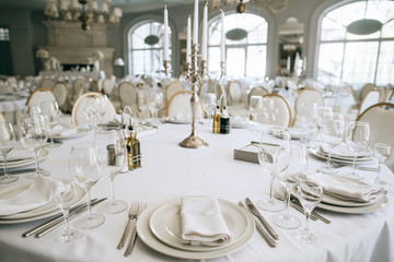 Elegant wedding reception white table arrangement restaurant, 
candlestick on table. Plates, forks...