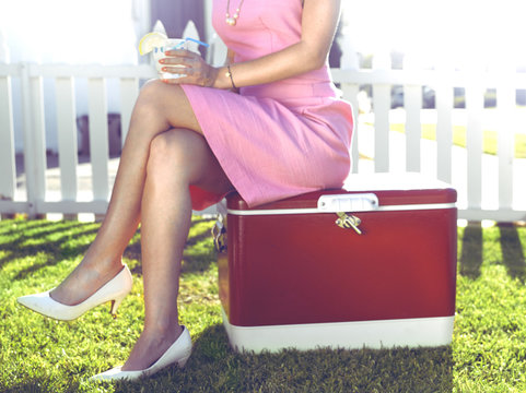 Fototapeta Glamorous woman sitting on vintage cooler in backyard